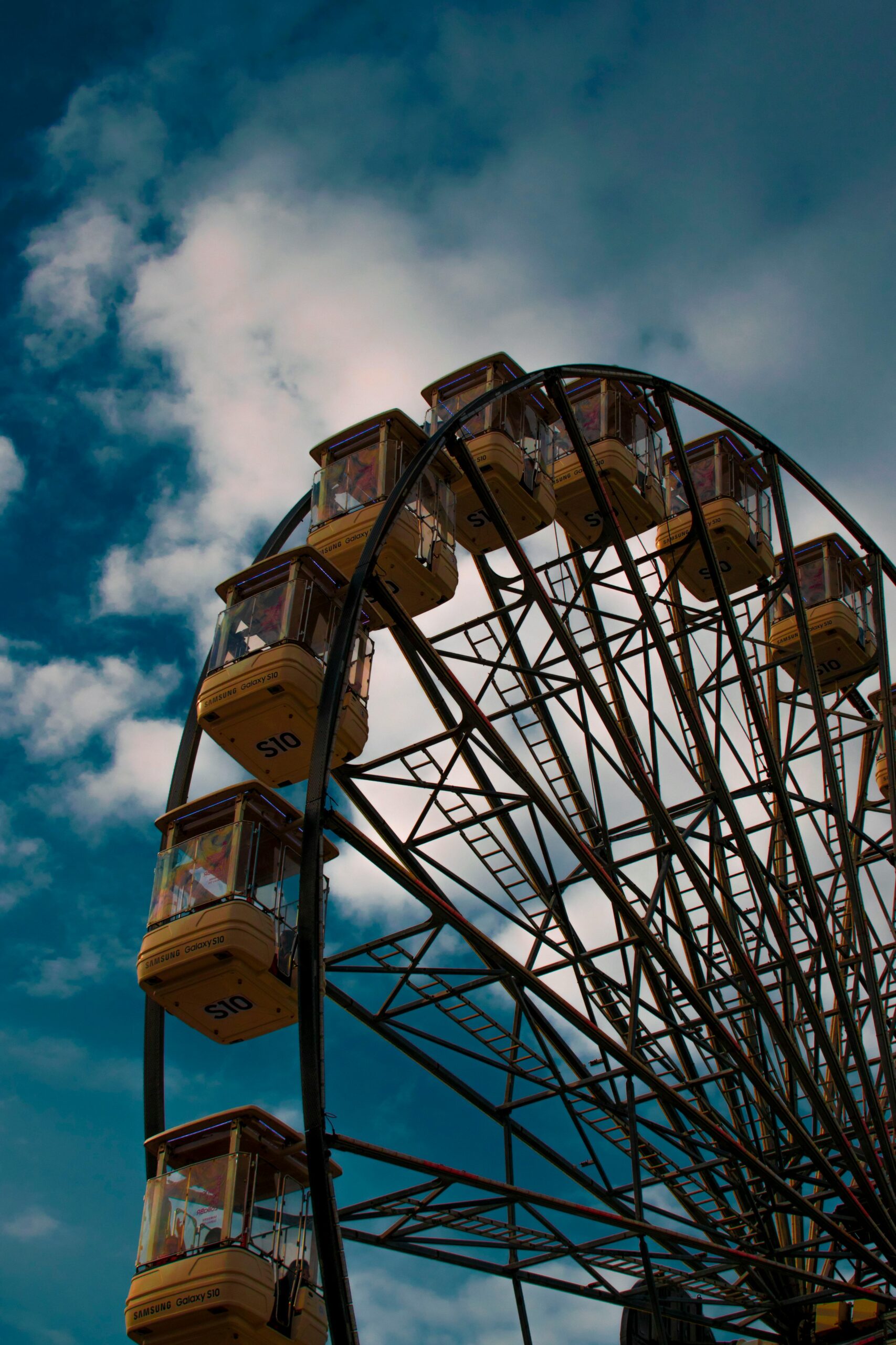 Grande roue rouge et jaune dans un parc d'attractions sous un ciel bleu.